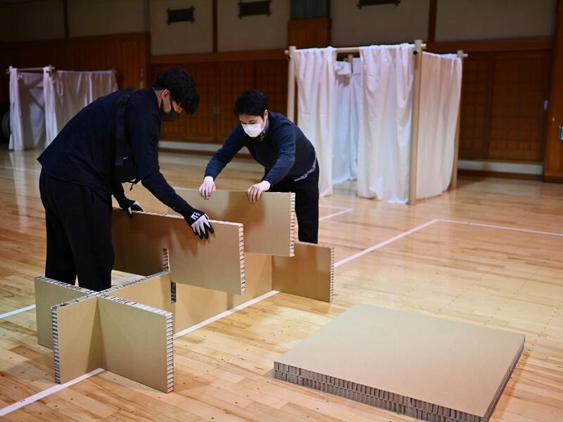 This photo taken on April 14, 2020 shows workers from Voluntary Architects' Network building partitions and beds at a shelter provided by Kanagawa prefecture for people who can’t afford to rent an apartment and used to stay at designated internet cafes, which are closed due to the COVID-19 coronavirus outbreak state of emergency, at a judo sport hall in Yokohama, Kanagawa prefecture. CHARLY TRIBALLEAU / AFP