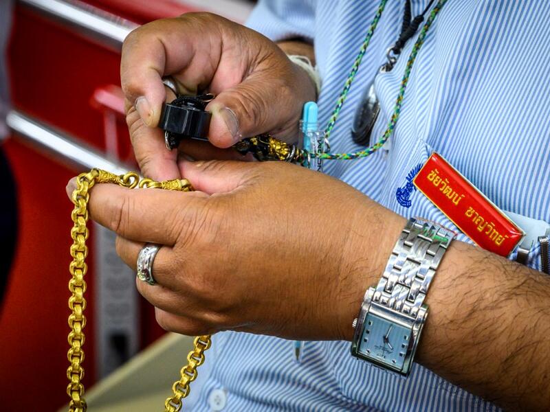 An employee checks a gold chain offered for sale in a gold shop in Bangkok's Chinatown on April 15, 2020. Hundreds of Bangkok residents rushed to goldsmith shops in order to sell their jewelries as gold prices reached its highest levels since 2012. Mladen ANTONOV / AFP
