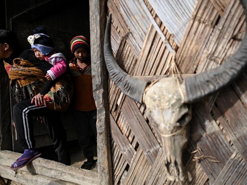 This photo taken on February 9, 2020 shows people leaving a Union Solidarity and Development Party house in Karmawlawyi village in Myanmar's Sagaing region, near the border with India. The king of the Konyak tribe sleeps in Myanmar, but eats in India -- his house, village and people divided by a mountain border which serves as a vulnerable lifeline now severed by a coronavirus lockdown.  Ye Aung THU / AFP
