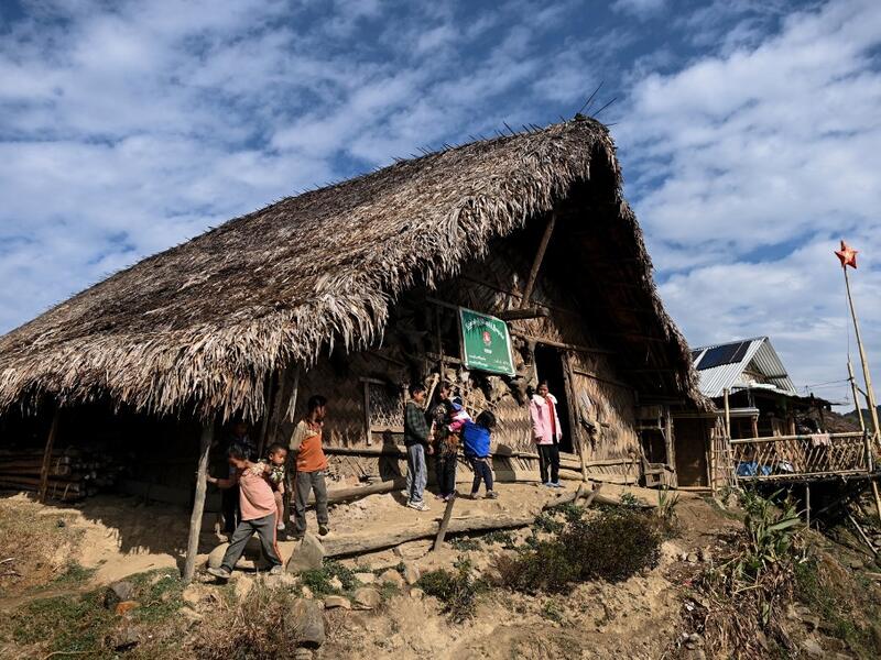 This photo taken on February 9, 2020 shows people standing outside a Union Solidarity and Development Party house in Karmawlawyi village in Myanmar's Sagaing region, near the border with India. The king of the Konyak tribe sleeps in Myanmar, but eats in India -- his house, village and people divided by a mountain border which serves as a vulnerable lifeline now severed by a coronavirus lockdown.  Ye Aung THU / AFP