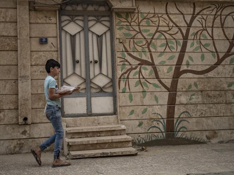 A Syrian boy carries bread back to his home in the city of Qamishli in Syria's northeastern Hasakeh province on April 24, 2020, on the first day of the Muslim holy fasting month of Ramadan despite the COVID-19 coronavirus pandemic. DELIL SOULEIMAN / AFP