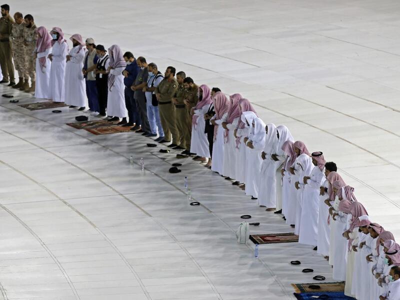 A picture taken on April 24, 2020, shows Saudi men performing prayers next to the Kaaba in Mecca's Grand Mosque, Islam's holiest site, on the first day of the Islamic holy month of Ramadan, amid unprecedented bans on family gatherings and mass prayers due to the coronavirus (COVID-19) pandemic. STR / AFP