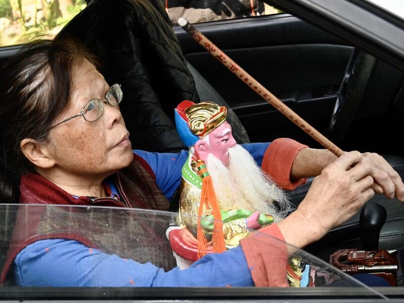 In this picture taken on March 17, 2020, a woman takes her new Taoist god statue home after it was restored by sculptor Lin Hsin-lai at his workplace in Taoyuan, northern Taiwan. Every spare surface of Lin Hsin-lai's four-storey shop is crammed with a pantheon of Taiwan's celestial beings, testament to the decades he has spent sheltering and restoring unwanted statues of gods.  Sam Yeh / AFP