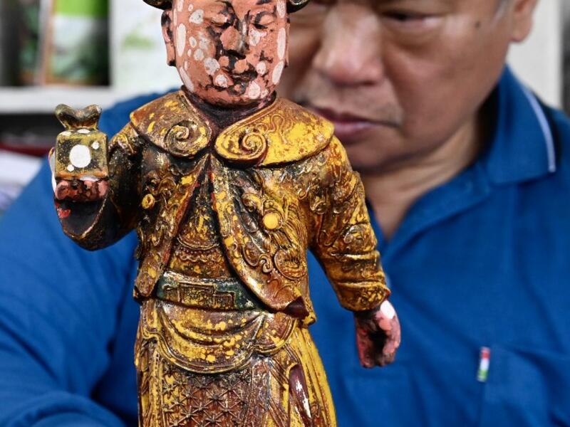 In this picture taken on March 17, 2020, sculptor Lin Hsin-lai restores a Taoist god statue at his workplace in Taoyuan, northern Taiwan on March 17, 2020. Every spare surface of Lin Hsin-lai's four-storey shop is crammed with a pantheon of Taiwan's celestial beings, testament to the decades he has spent sheltering and restoring unwanted statues of gods.  Sam Yeh / AFP