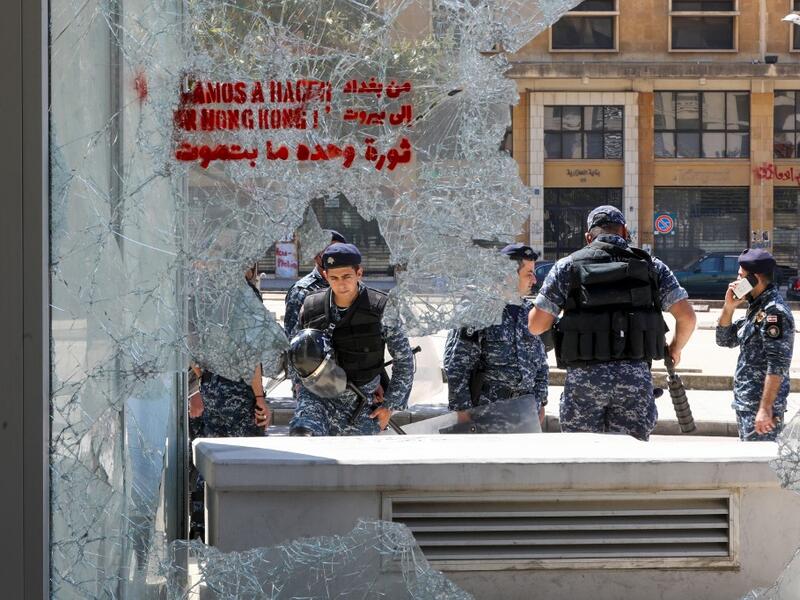 Members of the Lebanese security forces are seen through a broken store window in the downtown area of the capital Beirut, during an anti-government demonstration marking International Workers' Day (Labour Day), on May 1, 2020. ANWAR AMRO / AFP