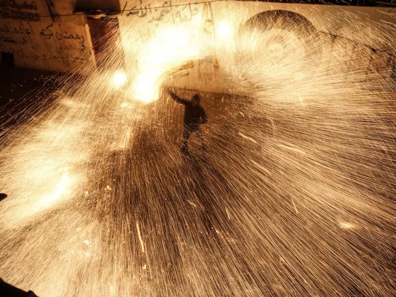 A Palestinian youth swings a homemade sparkler firework as people celebrate on a night of the Muslim holy month of Ramadan in Rafah refugee camp, in the southern Gaza Strip, on May 4, 2020. MAHMUD HAMS / AFP
