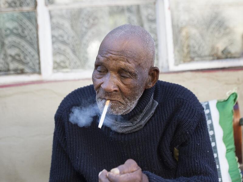 Fredie Blom enjoys a cigarette as he celebrates his 116th birthday at his home in Delft, near Cape Town, on May 8, 2020. According to 'Oupa' (grandfather) Fredie and his identity card, he was born in 1904, making him one of the oldest men in the world. RODGER BOSCH / AFP