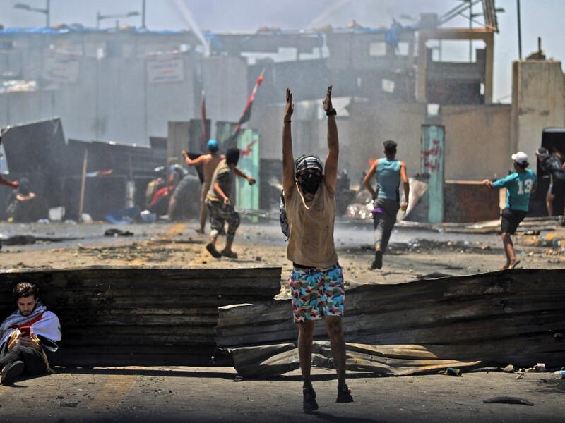 Iraqi protesters hurl rocks toward security forces as they clash with them during an anti-government demonstration on Al-Jumhuriyah bridge in the capital Baghdad, on May 10,2020. Modest anti-government rallies resumed in some Iraqi cities today, clashing with security forces and ending months of relative calm just days after Prime Minister Mustafa Kadhemi's government came to power. AHMAD AL-RUBAYE / AFP