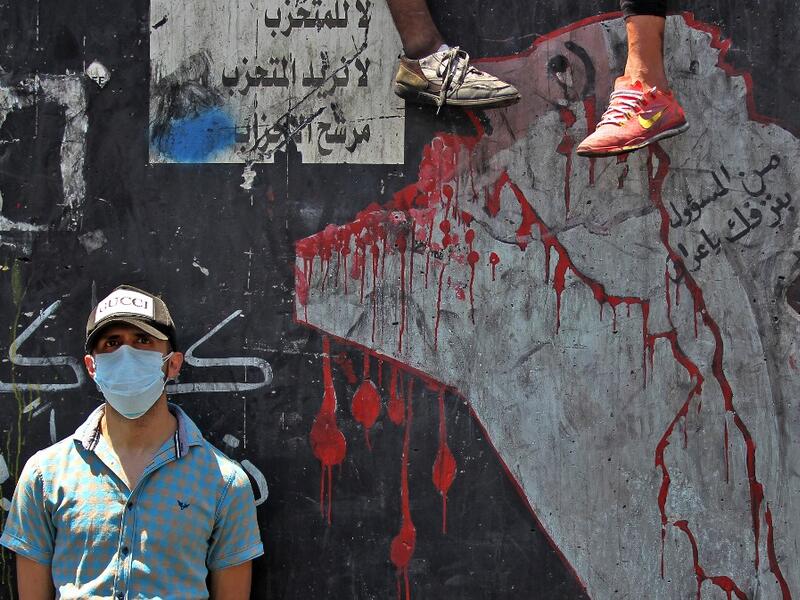 An Iraqi protester, wearing a protective mask, is pictured on the Al-Jumhuriyah bridge in the capital Baghdad on May 11, 2020, during an anti-government demonstration. Modest anti-government rallies resumed in some Iraqi cities Sunday, clashing with security forces and ending months of relative calm just days after Prime Minister Mustafa Kadhemi's government came to power. The protests first erupted in Baghdad and Shiite-majority southern cities in October, demanding an end to corruption and unemployment an