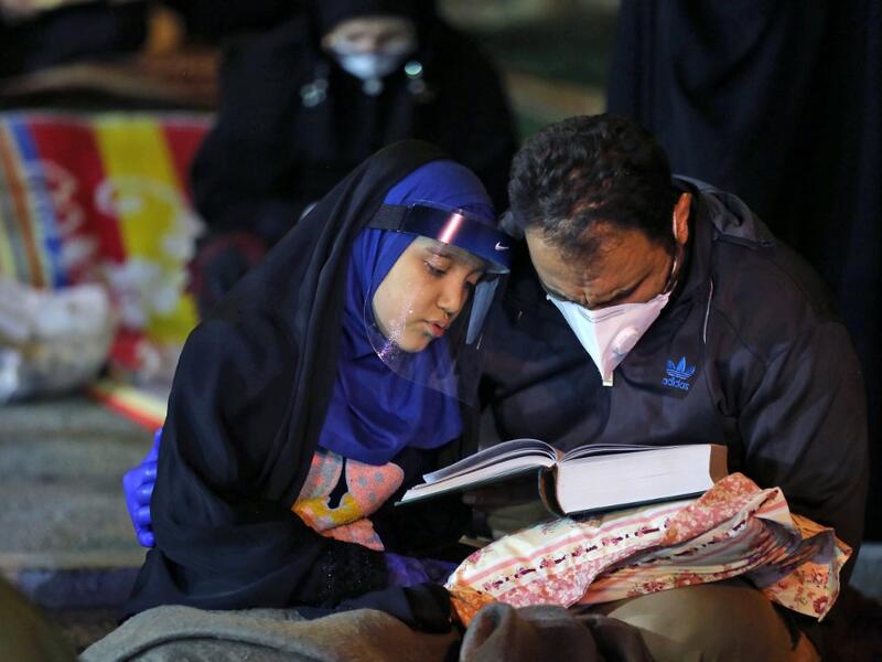 Iranians wearing face masks against the Covid-19 coronavirus attend Laylat al-Qadr prayers, one of the holiest nights during the Muslim fasting month of Ramadan, outside a mosque in the Tehran, on May 13, 2020. ATTA KENARE / AFP