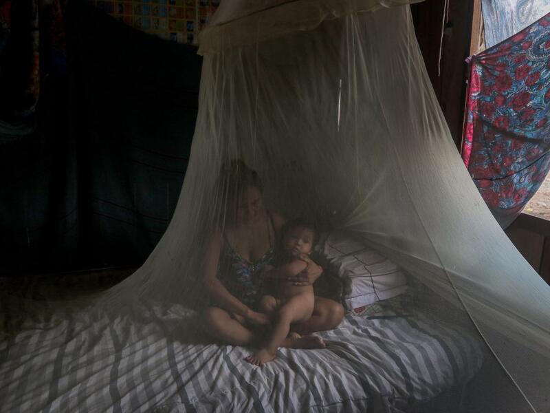 Satere-Mawe indigenous mother Priscila Tavares Batista, 36 remains in a bed protected by a mosquito net with her son Jone Tavares, 2, after being treated with medicinal herbs after showing symptoms of COVID-19, in the Wakiru community, in Taruma neighbourhood, a rural area west of Manaus, Amazonas State, Brazil, on May 17, 2020, during the novel coronavirus pandemic.Ricardo OLIVEIRA / AFP