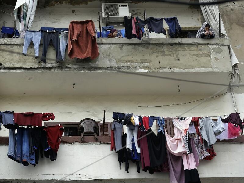 A woman stands next to laundry lines hanging out to dry on a balcony in the Bab al-Tabbaneh neighbourhood of Lebanon's northern city of Tripoli on June 3, 2020. Thousands of residents of Lebanon's northern Tripoli struggle to put food on the table, as the country's worst economic crisis in decades has picked up in speed in recent weeks, with food prices rising by more than 70 percent since the autumn. Inflation has been a blow in the country where more than 45 percent of the country's population now lives b