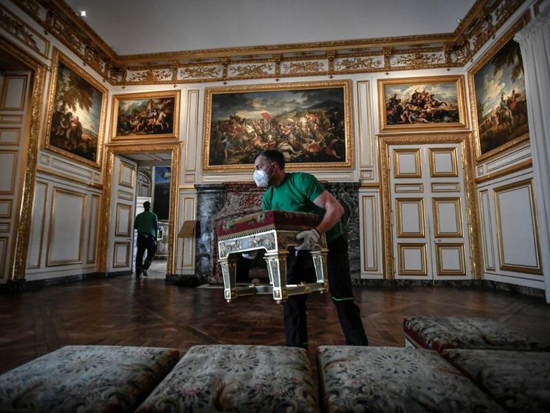A worker carries furniture in the Galerie des Glaces (Hall of Mirrors) at the Chateau de Versailles (Palace of Versailles) in Versailles near Paris, on June 5, 2020 on the eve of it re-opening after 82 days of closure due to the novel coronavirus (COVID-19) outbreak. The Palace of Versailles -- France's big tourist attraction with nearly 10 million tourists a year - will open on June 6 with no US or Asia tourists who represent 30% of its visitors. STEPHANE DE SAKUTIN / AFP