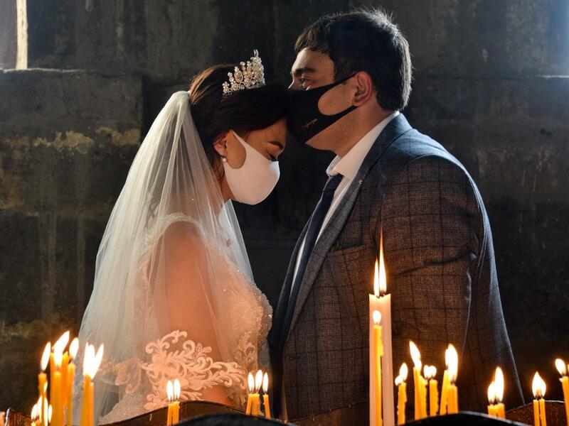A bride and a bridegroom wearing protective face masks exchange kisses during a wedding ceremony in a church in the Saghmosavan village outside Yerevan on June 14, 2020, as the country tries to curb the spread of the COVID-19, the disease caused by the novel coronavirus. Karen MINASYAN / AFP
