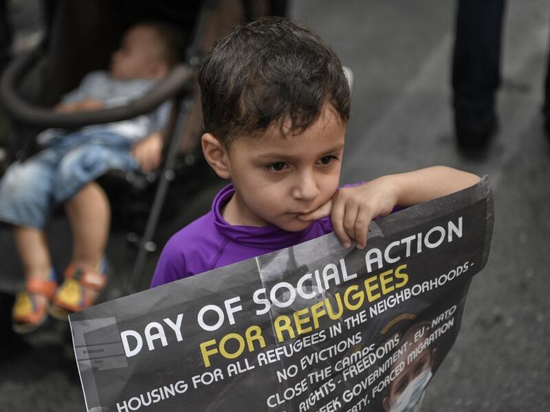 A young child holds a poster as he joins refugees participating in a rally in Athens on June 20, 2020, marking World Refugee Day aS THEY demand rights and housing for refugees and migrants in Greece. Louisa GOULIAMAKI / AFP