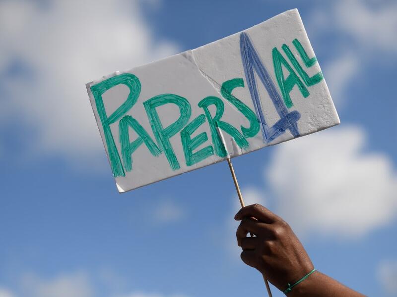 A woman holds a placard reading "Papers for all" during a migrant´s demonstration in Barcelona on June 20, 2020, marking World Refugee Day and demanding legal papers for refugees and migrants in Spain. Josep LAGO / AFP
