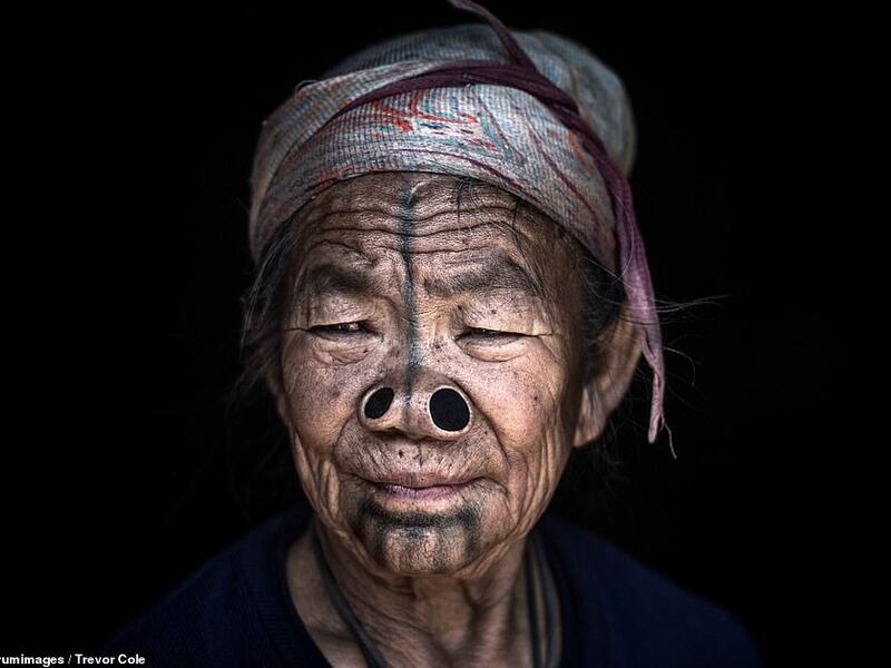 Striking images reveal the distinctive facial features of the Konyak tribe from North Eastern India, thought to be over 80 years old. A woman sporting two nose plugs and black markings across her face gazes wistfully out of the shot. (Mediadrumimages/ Trevor Cole)