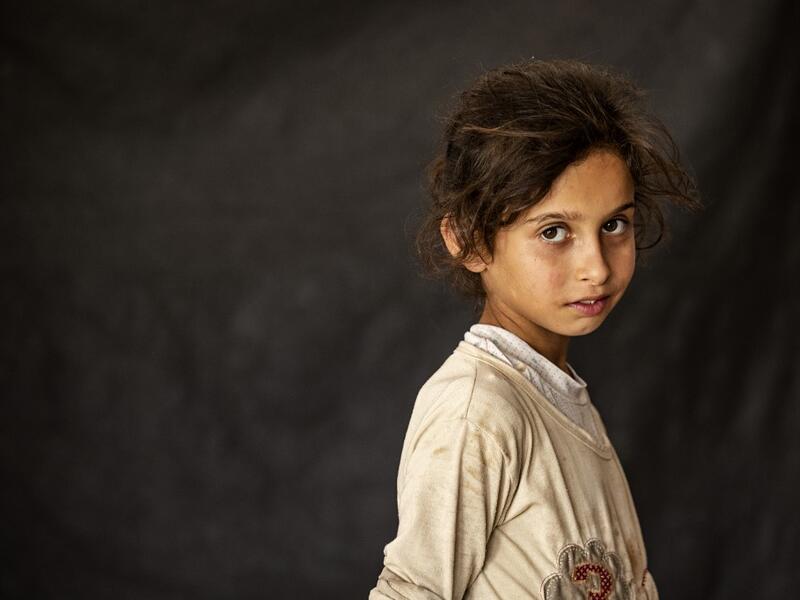 A girl poses for a picture while at a school building where Syrians -- displaced from the area of Ras al-Ain by the Turkish offensive on the northeast -- are staying in the city of Hasakah, on June 30, 2020. Delil SOULEIMAN / AFP