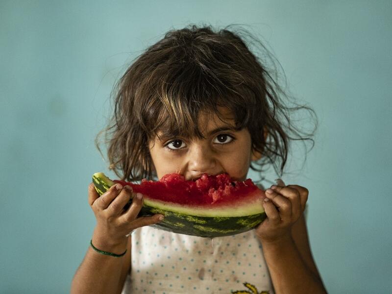 A girl eats a watermelon slice while at a school building where Syrians -- displaced from the area of Ras al-Ain by the Turkish offensive on the northeast -- are staying in the city of Hasakah, on June 30, 2020. Delil SOULEIMAN / AFP
