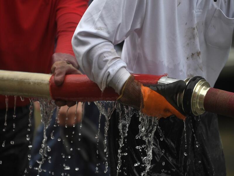 People clear debris and mud outside homes following heavy rains and flooding in the village of Gero, Gifu prefecture on July 9, 2020. Japanese emergency services and troops were scrambling to reach thousands of homes cut off by devastating flooding and landslides that have killed dozens and caused widespread damage. Philip FONG / AFP
