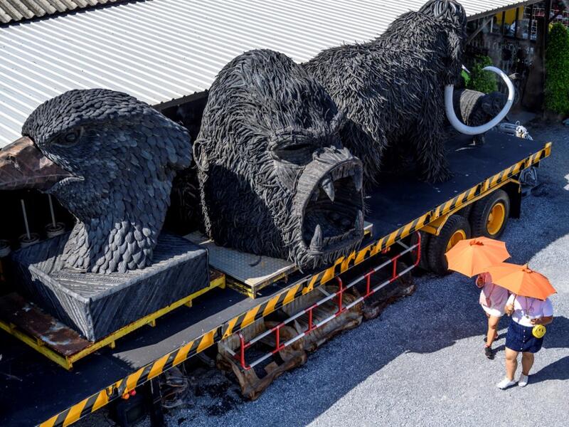 This photograph taken on July 18, 2020 shows tourists walking in front of giant sculptures of animals made of used car tyres at the Ban Hun Lek museum in Ang Thong, some 100km north of Bangkok. "Ban Hun Lek" or "The House of Steel Robots" is a museum where a collective of artists display their scrap metal creations depicting popular comics and sci-fi film characters. Mladen ANTONOV / AFP