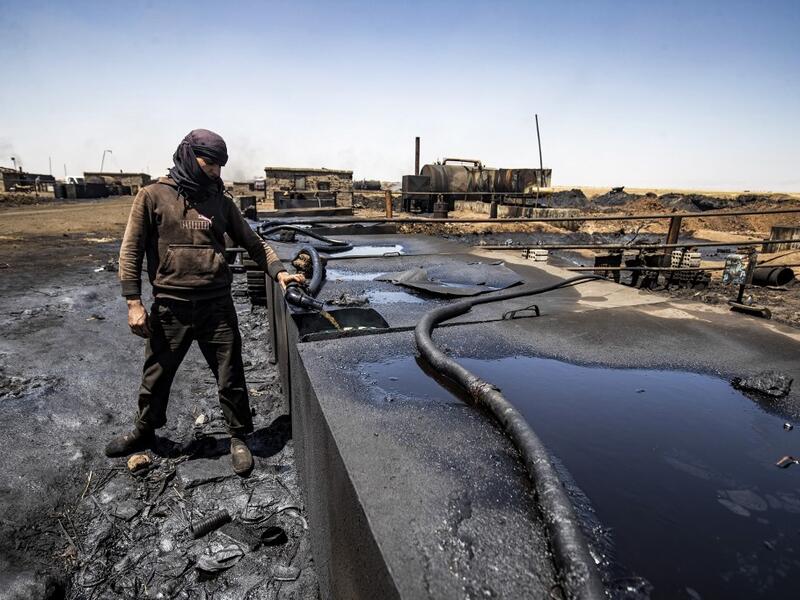 A man works at a makeshift refinery using burners to distill crude oil in the village of Bishiriya in the countryside near the town of Qahtaniya west of Rumaylan (Rmeilan) in Syria's Kurdish-controlled northeastern Hasakeh province, on July 19, 2020. DELIL SOULEIMAN / AFP