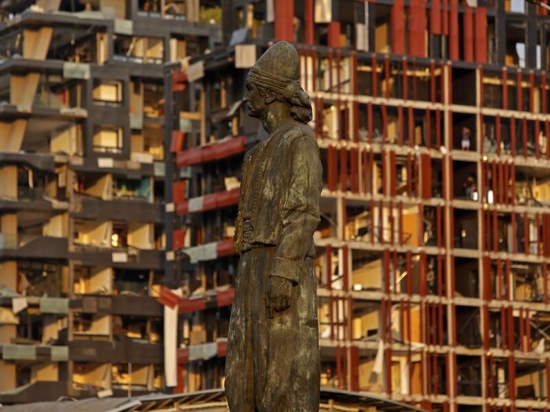 The statue of the Lebanese Emigrant stands intact in front of damaged buildings at the entrance of Beirut's port following a powerful explosion in its vicinity in Lebanon's capital on August 4, 2020. Marwan TAHTAH / AFP