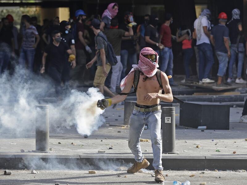 A Lebanese protester throws a tear-gas canister back at security forces in downtown Beirut on August 8, 2020, following a demonstration against a political leadership they blame for a monster explosion that killed more than 150 people and disfigured the capital Beirut. JOSEPH EID / AFP