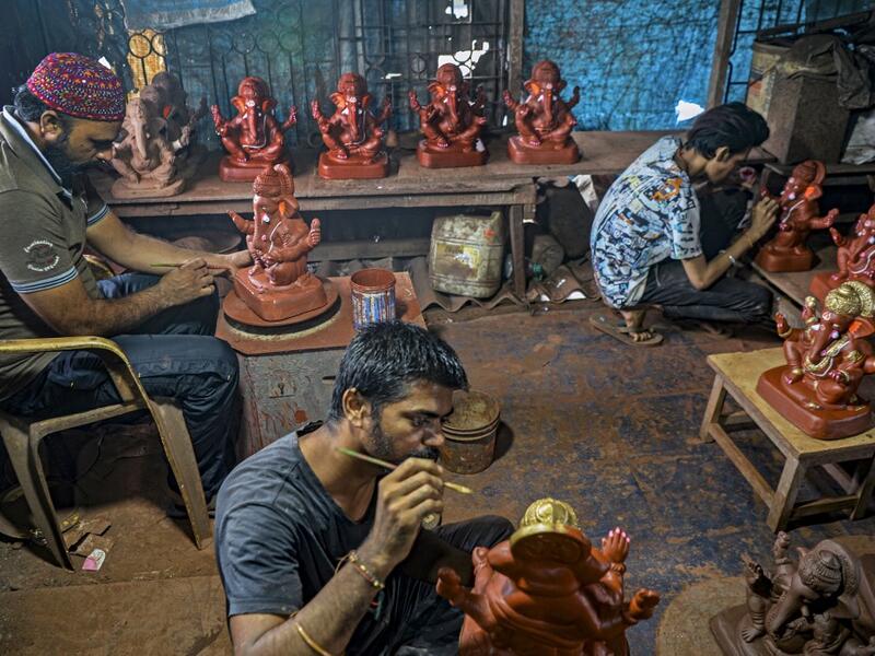 In this picture taken on August 15, 2020, Muslim potter Yusuf Zakaria Galwani (L) along with his staff, work on the idols of elephant headed Hindu god Ganesha at his workshop at Kumbharwada inside the Dharavi slums in Mumbai. After the coronavirus pandemic clobbered his pottery business, a Muslim artisan from India's largest slum turned to a Hindu god to revive his fortunes by making environmentally-friendly Ganesha idols for an upcoming festival. In Mumbai's Dharavi slum, Galwani worked alongside his two b
