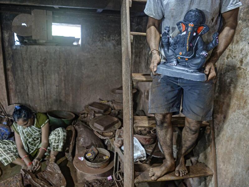 In this picture taken on August 15, 2020, an artisan carries a clay idol of elephant headed Hindu god Ganesha at Muslim potter Yusuf Zakaria Galwani's workshop at Kumbharwada inside the Dharavi slums in Mumbai. After the coronavirus pandemic clobbered his pottery business, a Muslim artisan from India's largest slum turned to a Hindu god to revive his fortunes by making environmentally-friendly Ganesha idols for an upcoming festival. In Mumbai's Dharavi slum, Galwani worked alongside his two brothers to crea