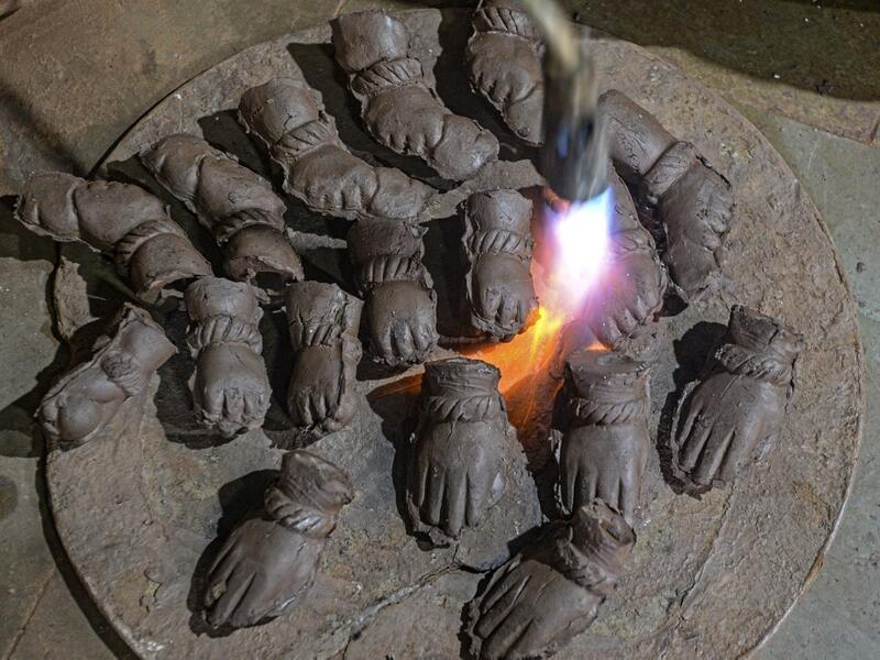 In this picture taken on August 15, 2020, an artisan uses a blowtorch to dry the hands of clay idols of elephant headed Hindu god Ganesha at Muslim potter Yusuf Zakaria Galwani's workshop at Kumbharwada inside the Dharavi slums in Mumbai. After the coronavirus pandemic clobbered his pottery business, a Muslim artisan from India's largest slum turned to a Hindu god to revive his fortunes by making environmentally-friendly Ganesha idols for an upcoming festival. In Mumbai's Dharavi slum, Galwani worked alongs