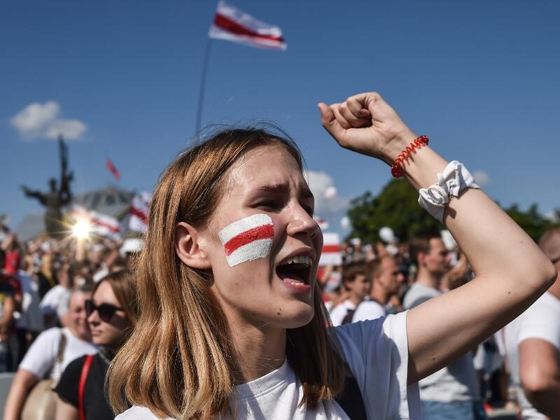 A woman Belarus opposition supporter with a drawing of a former white-red-white flag of Belarus used in opposition to the government punches the air during a demonstration in central Minsk on August 16, 2020. The Belarusian strongman, who has ruled his ex-Soviet country with an iron grip since 1994, is under increasing pressure from the streets and abroad over his claim to have won re-election on August 9, with 80 percent of the vote. Sergei GAPON / AFP