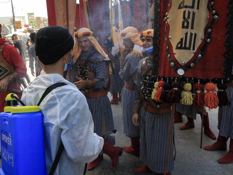 Ashura re-enactors in costume are doused, as a COVID-19 coronavirus pandemic precaution, while playing out a procession commemorating the entry of Imam Hussein and his family and retinue into Karbala, as Shiite Muslims mark the Ashura period in Iraq's central holy shrine city on August 22, 2020. Ashura is a period of mourning in remembrance of the seventh-century martyrdom of Prophet Mohammad's grandson Imam Hussein, who was killed in the battle of Karbala in modern-day Iraq, in 680 AD. Mohammed SAWAF / AFP