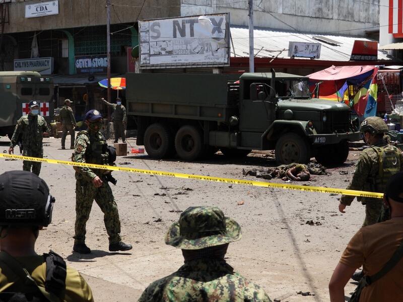 The bodies of victims (C) lie on the pavement as police and military personnel cordon off the site where an improvised bomb exploded next to a military vehicle in the town of Jolo on Sulu island on August 24, 2020. (AFP/File)
