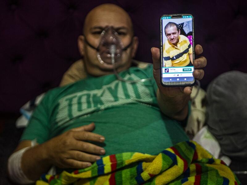 Venezuelan Wilmer Hernandez, 44, shows a picture of his father Wilmer Arcadio Hernandez, 63, as he remains connected to an oxygen tank in his home in Villa Maria del Triunfo, south of Lima, Peru, on June 25, 2020. Global deaths from the coronavirus have almost reached on September 25, 2020 the grim threshold of one million. Around one-third of fatalities were in Latin America, where countries with overstretched medical resources are preparing for a further onslaught. ERNESTO BENAVIDES / AFP