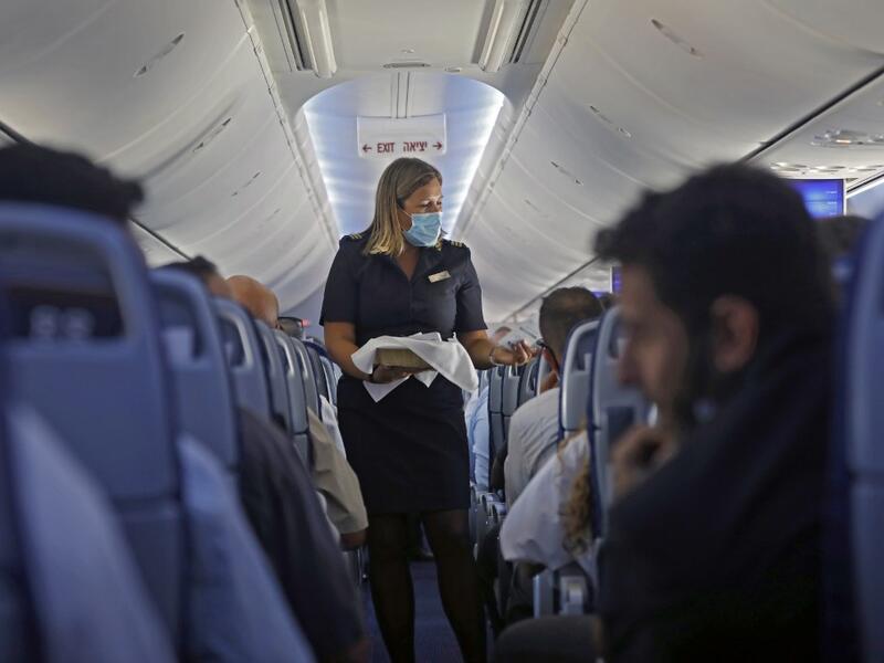 A flight attendant hands out chocolates with a greeting card to passengers on an El Al plane from Israel en route to Abu Dhabi, on August 31, 2020. A US-Israeli delegation including White House advisor Jared Kushner took off on a historic first direct commercial flight from Tel Aviv to Abu Dhabi to mark the normalisation of ties between the Jewish state and the UAE. NIR ELIAS / AFP
