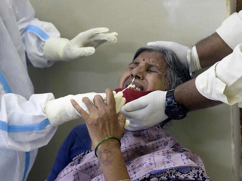 A health worker (L) wearing a Personal Protective Equipment (PPE) suit collects a swab sample from a woman to test for the Covid-19 coronavirus at a primary health centre in Hyderabad on September 3, 2020. NOAH SEELAM / AFP