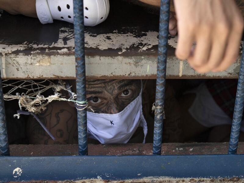 A member of the 18 gang looks on from an overcrowded cell at the Quezaltepeque prison, in Quezaltepeque, El Salvador, on September 4, 2020. Authorities from the General Directorate of Penal Centres (DGCP) visited three Salvadorean prisons, some of maximum security, to check the situation of inmates and carry out searches amid the COVID-19 novel coronavirus pandemic. Yuri CORTEZ / AFP