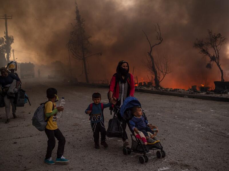 A woman and children flee flames major fire broke out in the Moria migrants camp on the Greek Aegean island of Lesbos, on September 9, 2020. 