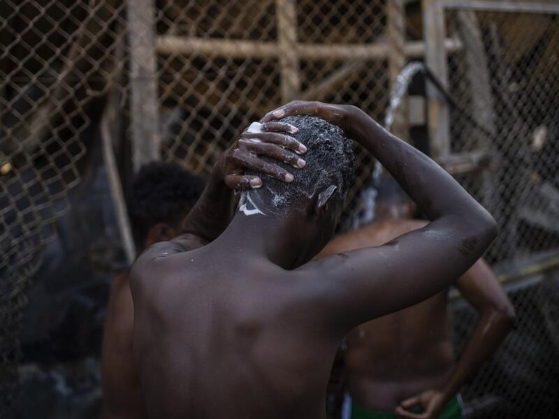 Migrants take shower Children walk in the burnt migrants camp of Moria on the Greek Aegean island of Lesbos on September 9, 2020 after a major fire broke out. Thousands of asylum seekers were left homeless on September 9 after a fire gutted Greece's largest migrant camp on Lesbos, plunging the island into crisis and provoking an outpouring of sympathy from around Europe and calls for reform of the refugee system. 