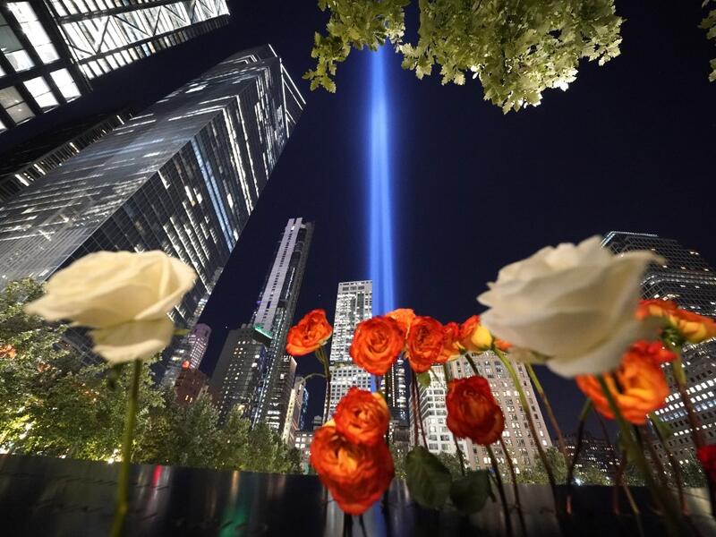Roses are seen on the 9/11 Memorial as the Tribute in Light art installation shines into the sky over Manhattan on September 11, 2020 in New York to mark the 19th anniversary of the 9/11 attacks. TIMOTHY A. CLARY / AFP
