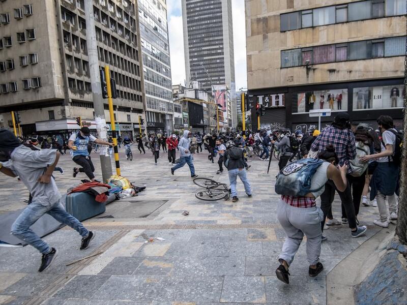 Demonstrators run for cover after clashes erupted during the fifth straight day of protests against police brutality in Bogota on September 13, 2020. Bogota's Mayor Claudia Lopez, apologized this Sunday for the abuses of the public force, in a ceremony that gathered relatives of the dead and wounded during the bloody protests that broke out five days ago against police brutality in Colombia. Juan BARRETO / AFP