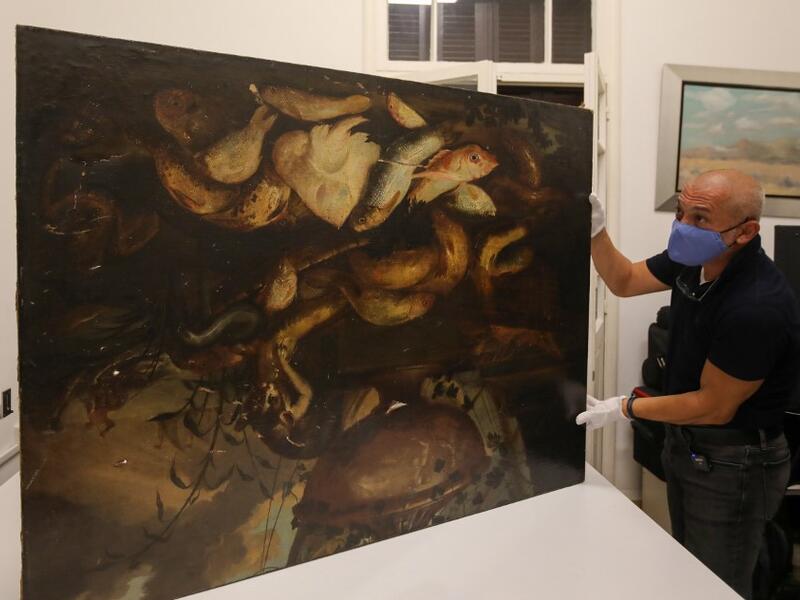 Gaby Maamary, a Lebanese artwork conservation specialist, examines a 17th-century painting by Italian painter Elena Recco, damaged in the Beirut port blast, at his studio in the capital Beirut on September 17, 2020. ANWAR AMRO / AFP