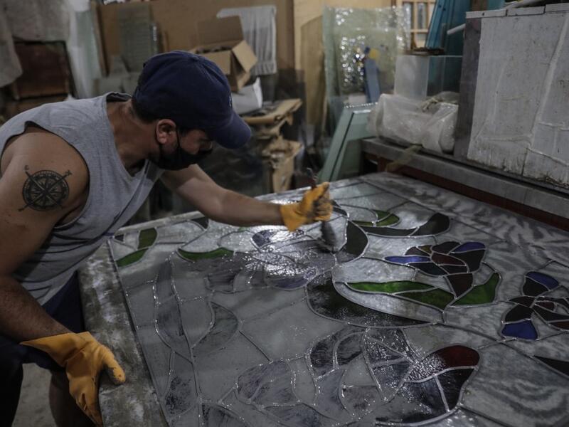 A collaborator of Lebanese stained glass artist Maya Husseini, works on a piece in her basement workshop on the outskirts of the capital Beirut, on September 18, 2020. ANWAR AMRO / AFP