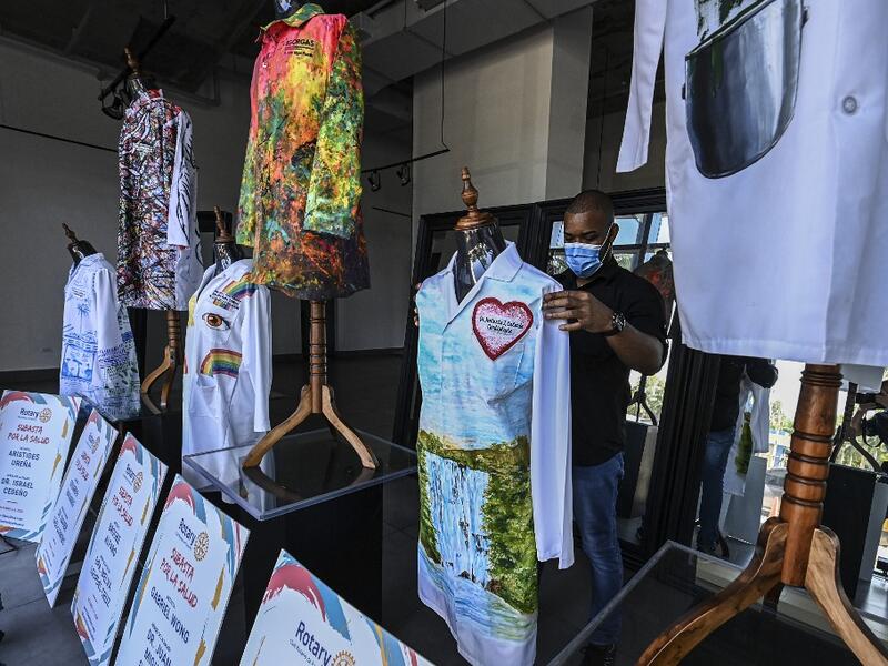 A gallery worker organizes white coats used by doctors fighting against COVID-19 and decorated by Panamanian artists, in Panama City, on September 26, 2020. More than 20 doctor's coats fighting against COVID-19 that were disinfected and painted by Panamanian artists will be auctioned off from October 1 to 4. The funds will go to 20 health centers. Luis ACOSTA / AFP