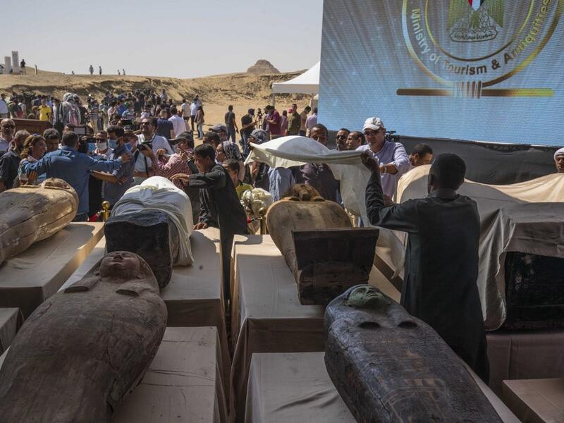A picture taken on October 3, 2020 shows Egyptian workers covering one of the sarcophaguses, excavated by the Egyptian archaeological mission which resulted in the discovery of a deep burial well with more than 59 human coffins closed for more than 2,500 years, displayed during a press conference at the Saqqara necropolis, 30 kms south of the Egyptian capital Cairo. They were unearthed south of Cairo in the sprawling burial ground of Saqqara, the necropolis of the ancient Egyptian capital of Memphis, a UNES