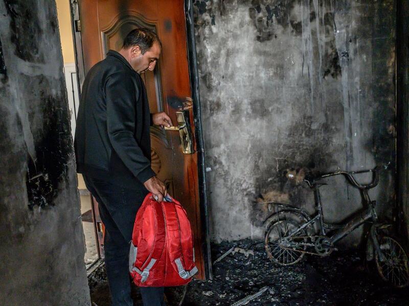 Razim Mehmedov, 40, holding his daughter's backpack stands in his flat that was damaged and burnt by shelling as residents return to their homes following a ceasefire during a military conflict between Armenia and Azerbaijan over the breakaway region of Nagorno-Karabakh, in the town of Terter, Azerbaijan, on October 10, 2020. Armenia and Azerbaijan traded accusations of new attacks on October 10 in breach of a ceasefire deal to end nearly two weeks of heavy fighting over the disputed Nagorno-Karabakh region