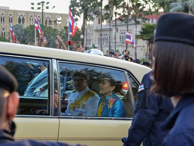 Thailand's Queen Suthida (C) and Prince Dipangkorn Rasmijoti (centre L) react inside a royal motorcade as it drives past a pro-democracy rally, as anti-government protesters (back) hold up their three-finger salute, in Bangkok on October 14, 2020. Teera NOISAKRAN / AFP