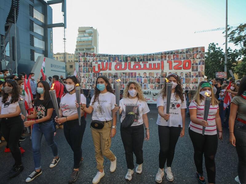 Lebanese protesters carry torches during a demonstration marking the one year anniversary of the beginning of a nationwide anti-government protest movement, in the capital Beirut on October 17, 2020. ANWAR AMRO / AFP