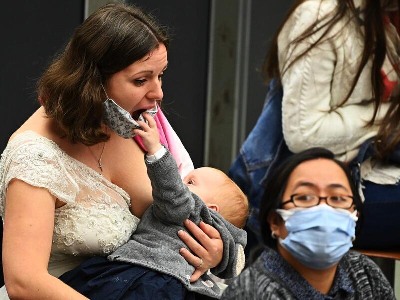 A woman breastfeeds her child, that jokes with her face mask, during the Pope Francis' weekly general audience at Paul VI hall on October 21, 2020, at the Vatican. Vincenzo PINTO / AFP